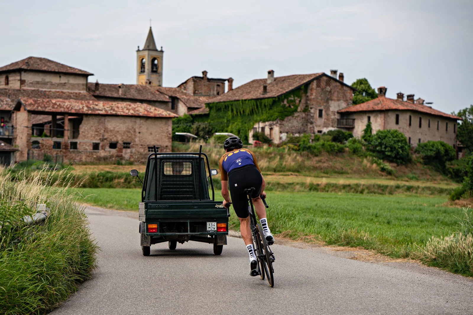 Cyclist in Rocket kit following an Ape van through the Italian countryside