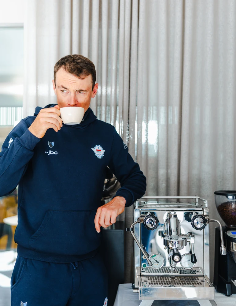 Yves Lampaert drinking coffee beside a Rocket espresso machine